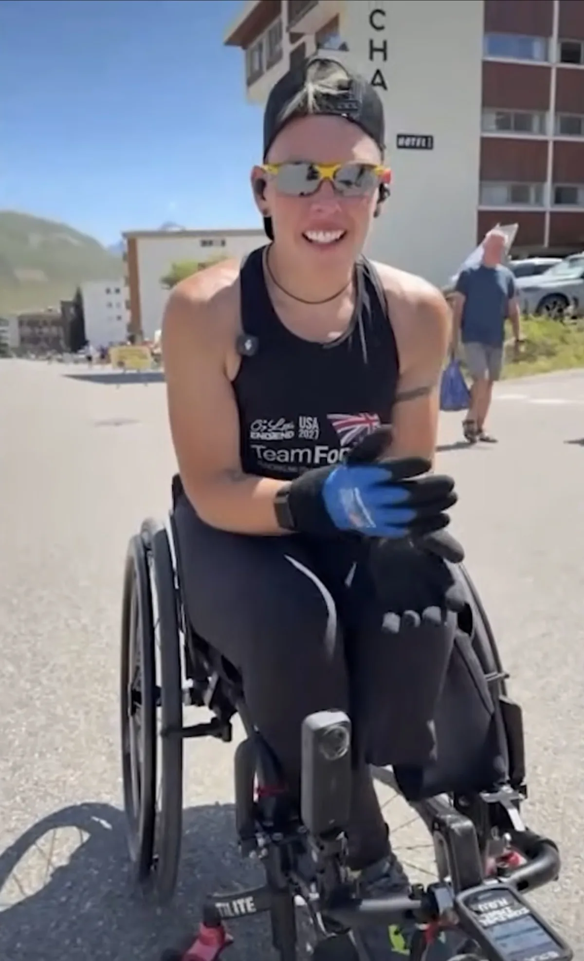 Lexi smiling in her wheelchair at the top of Alpe d'Huez